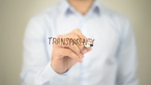 A man representing marketing management carefully pens the word "transparency" on a piece of paper.