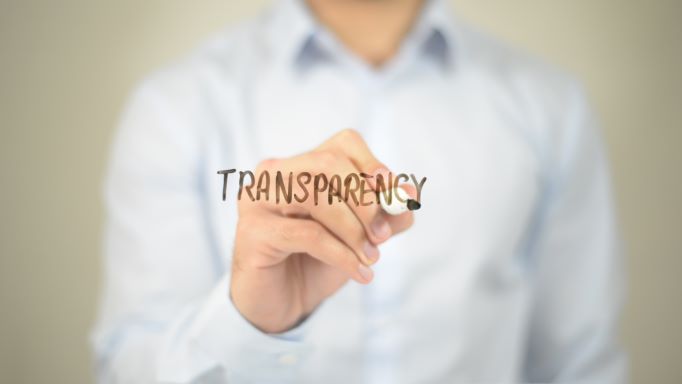 A man representing marketing management carefully pens the word "transparency" on a piece of paper.
