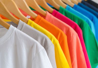 A row of colorful t-shirts on wooden hangers displayed in an online marketplace.